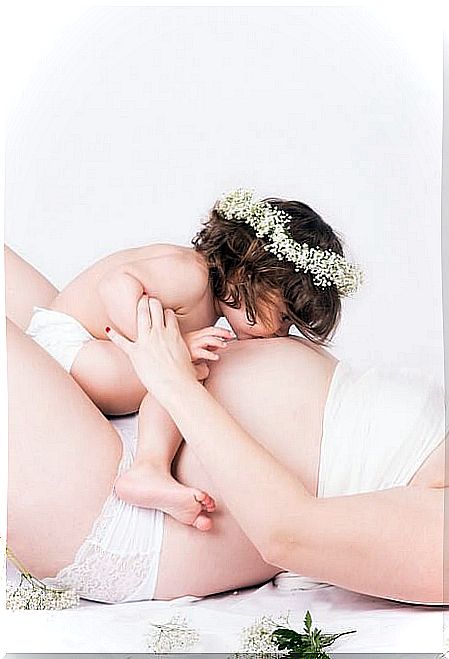 Child kisses pregnant belly for prenatal stimulation